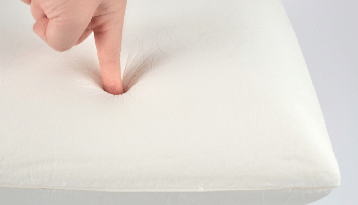 person checking softness of pillow with finger